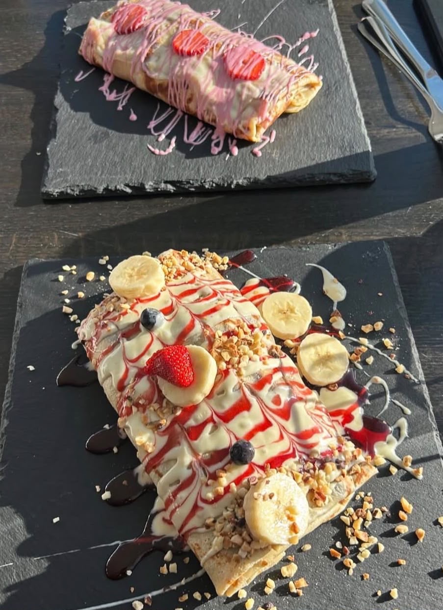 Zwei Crêpes mit weißer Schokolade, Erdbeeren, Bananen und Nüssen